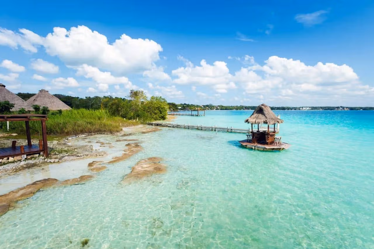 A thatched palapa on a pier over the clear, multi-toned water of the Bacalar lagoon