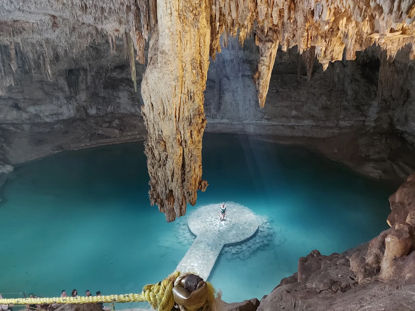 A single beam of light falling on the round stone platform at the center of Cenote Suytun