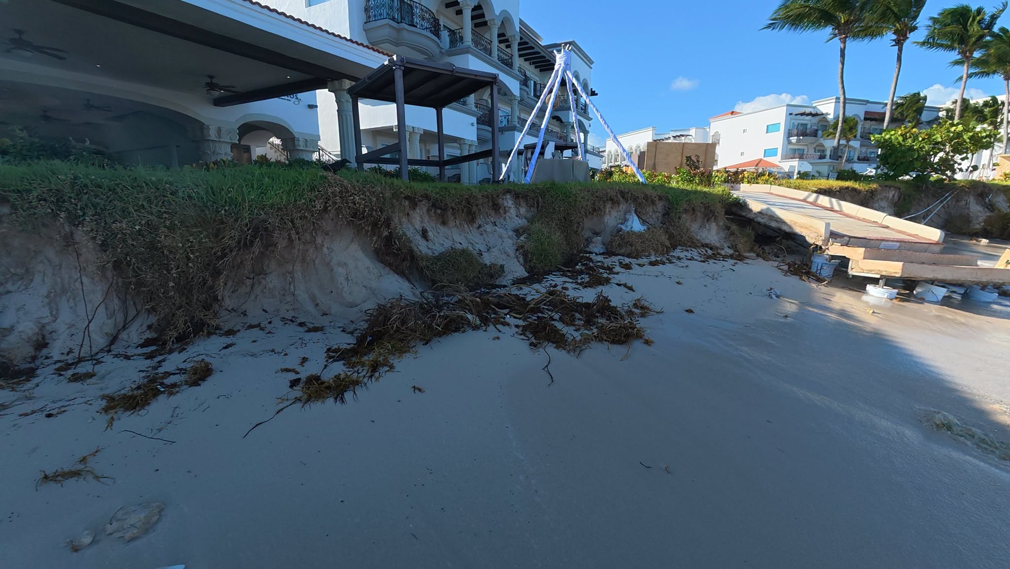 A steep eroded bank below a hotel garden at Playa Constituyentes, with a damaged access ramp