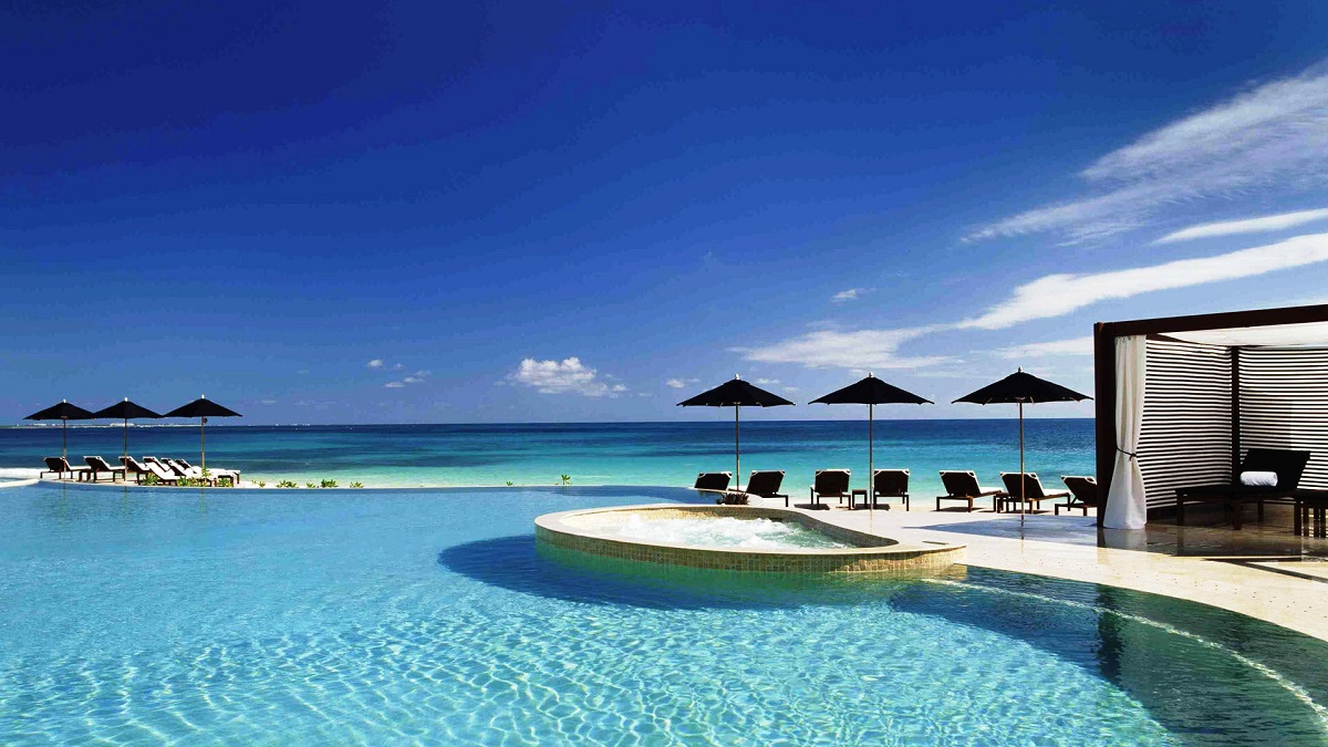 The black-parasol beachfront infinity pool at Rosewood Mayakoba above the Caribbean