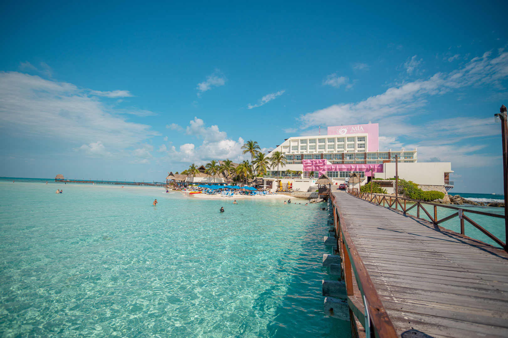 Wooden pier leading to a beachfront hotel on Isla Mujeres over clear shallow turquoise water