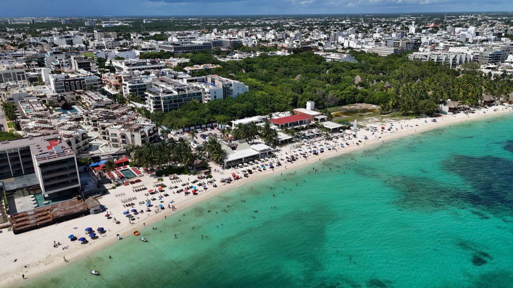 Aerial view of Playa Mamitas: beach clubs, loungers and swimmers along a wide white beach, with turquoise water offshore