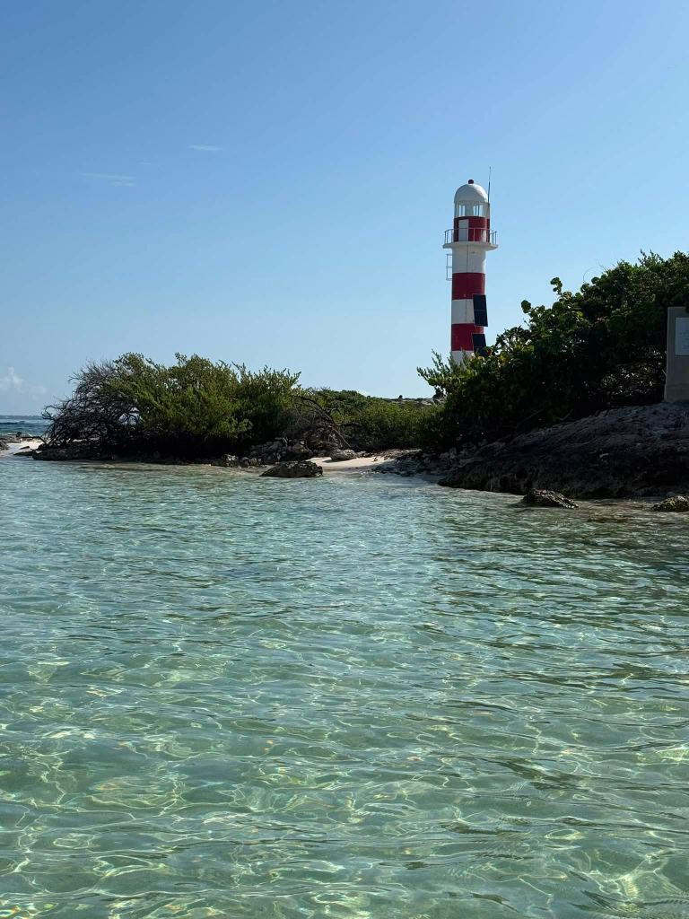 The red-and-white lighthouse at Punta Cancún above clear, shallow turquoise water