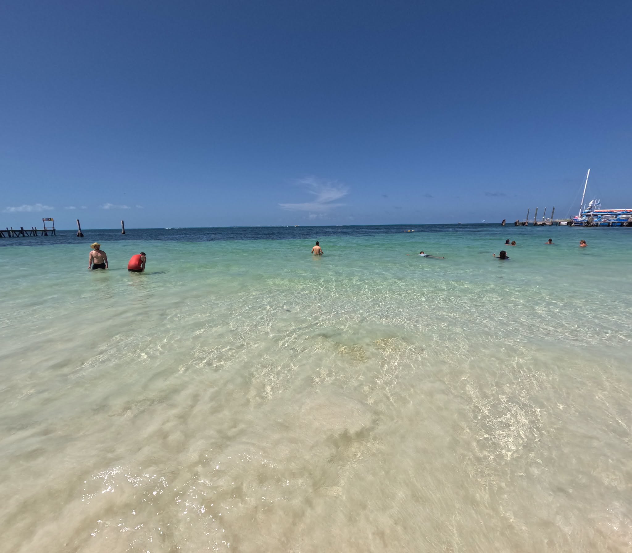 Crystal-clear shallow turquoise water at Playa Tortugas in Cancún, with people wading and swimming