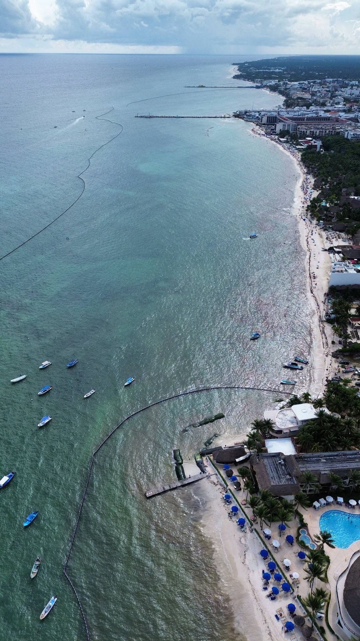 Aerial view of the Playa del Carmen town beaches from Constituyentes to Calle 44 in October 2026, with moored boats and the containment barrier offshore